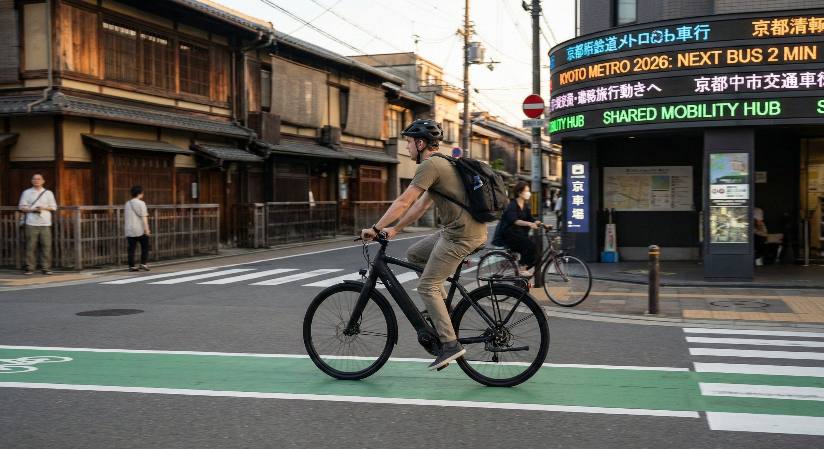 A traveler on a modern bicycle lane glides down a green-painted cycling in Kyoto, passing by a traditional wooden townhouse and a sleek, digital bus arrival information display