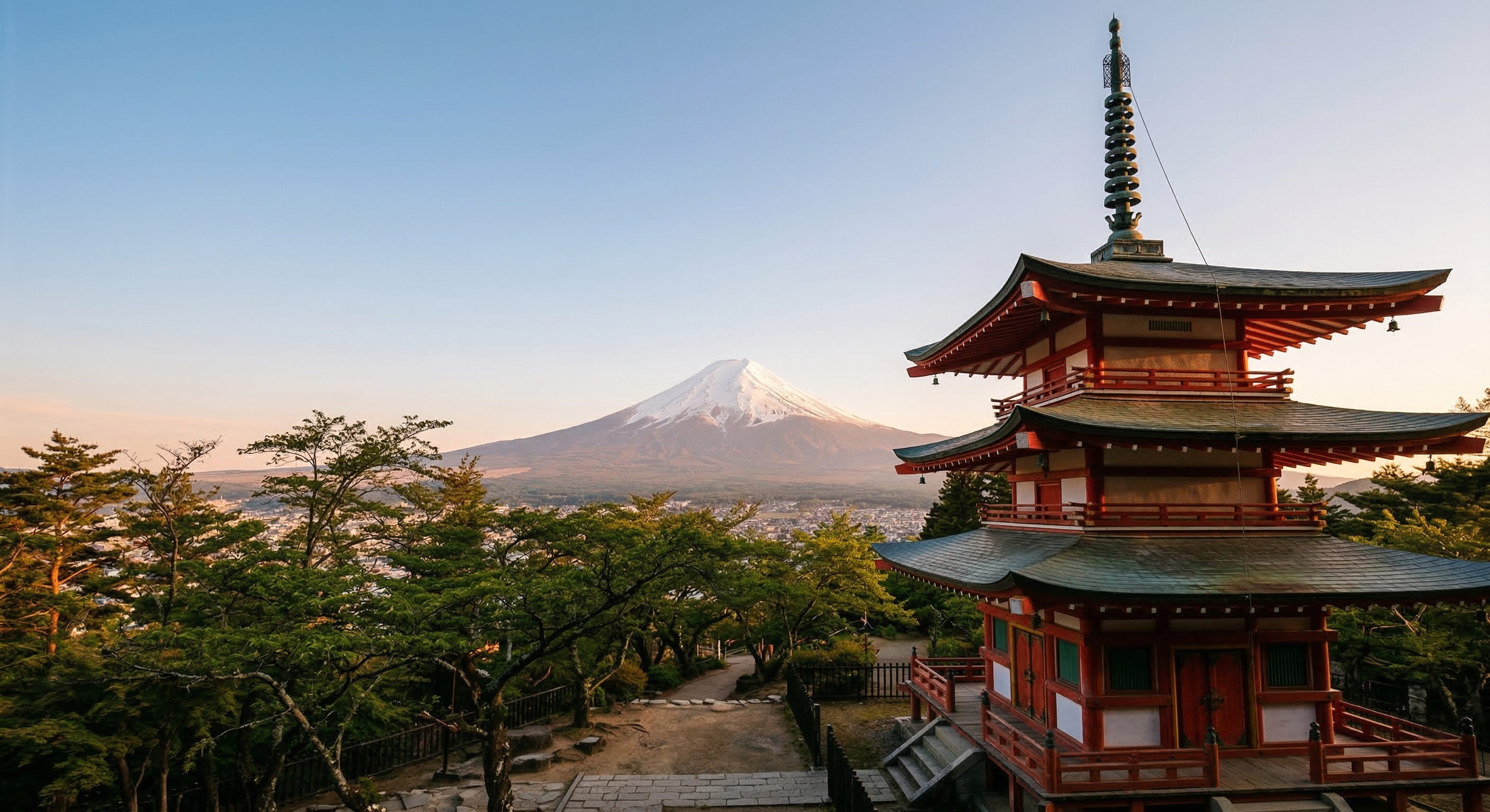The ornate bronze finial at the very top of the red pagoda points toward the sky, with the snowy peak of Mount Fuji visible in the soft background.