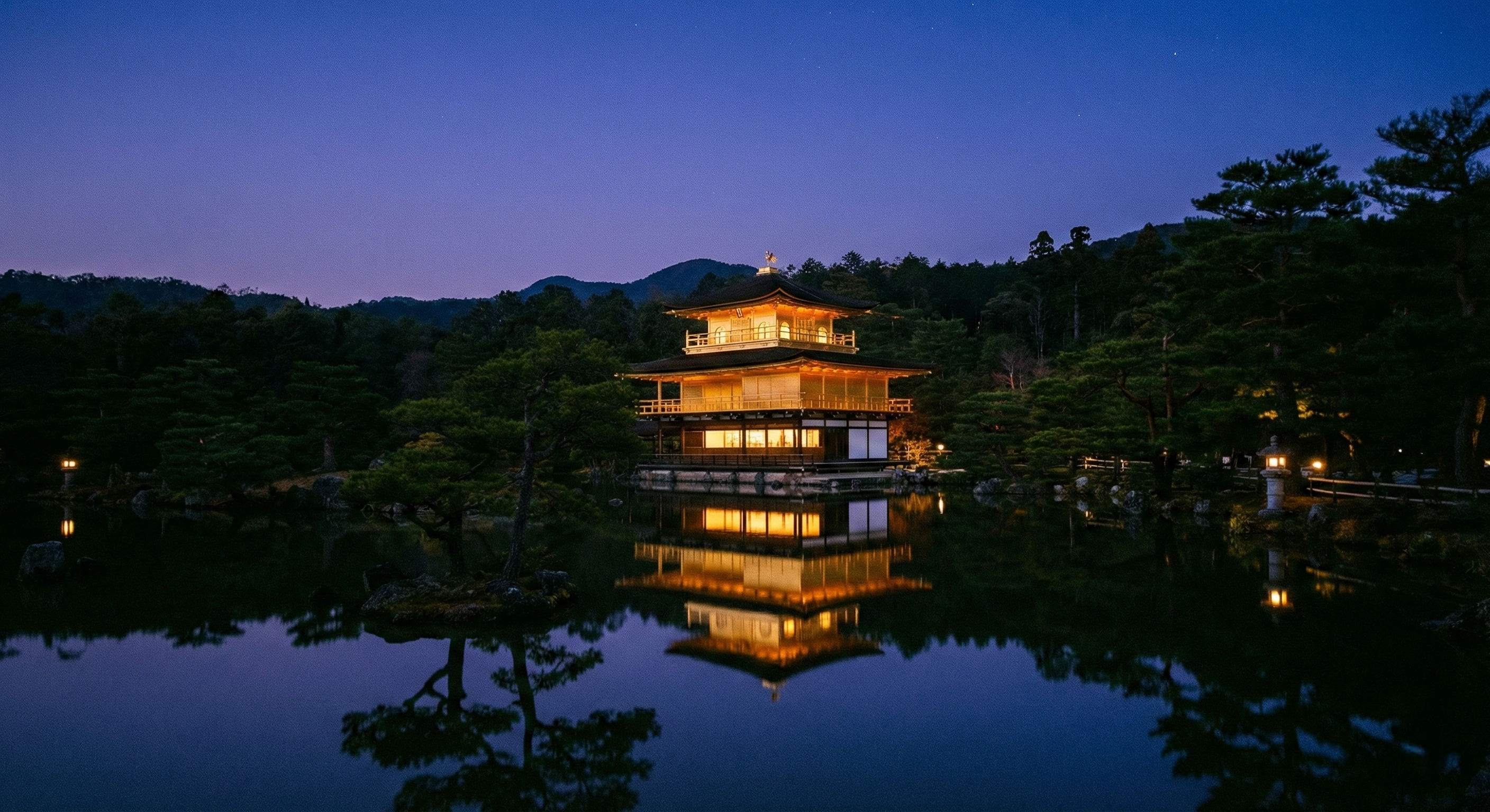 The Golden Pavilion (Kinkaku-ji) glowing warmly against deep blue twilight skies, perfectly reflected in the still pond during a private, after-hours viewing with zero crowds visible.