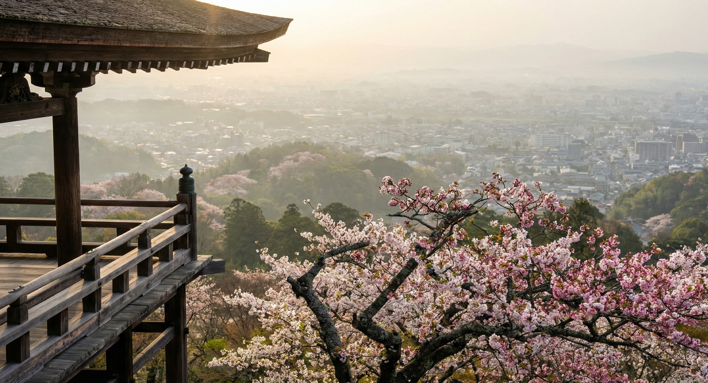 A breathtaking view from a mountain temple balcony overlooking the distant Kyoto valley, featuring blooming cherry blossoms in the foreground and a hazy city landscape branches in the background.